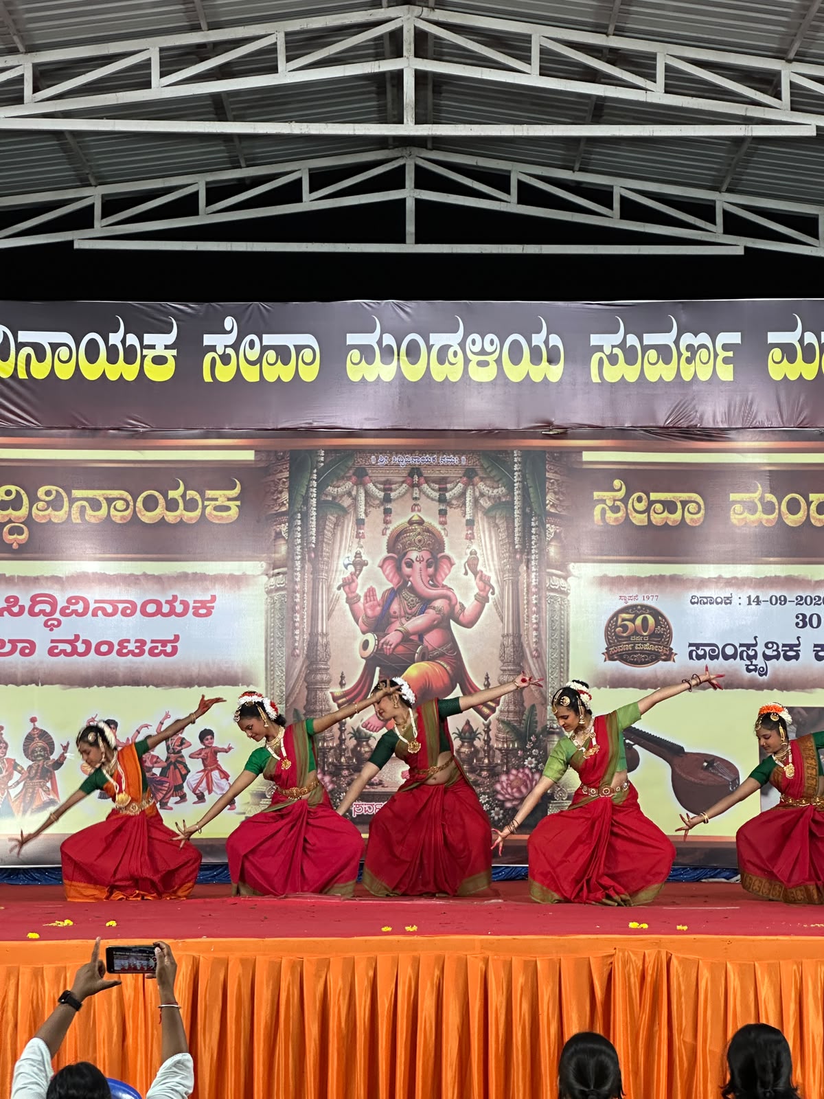 Dancers extending their arms in a synchronised Bharatanatyam stage pose