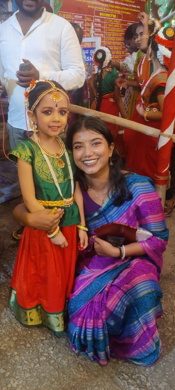 A teacher smiling alongside a young dancer in traditional costume