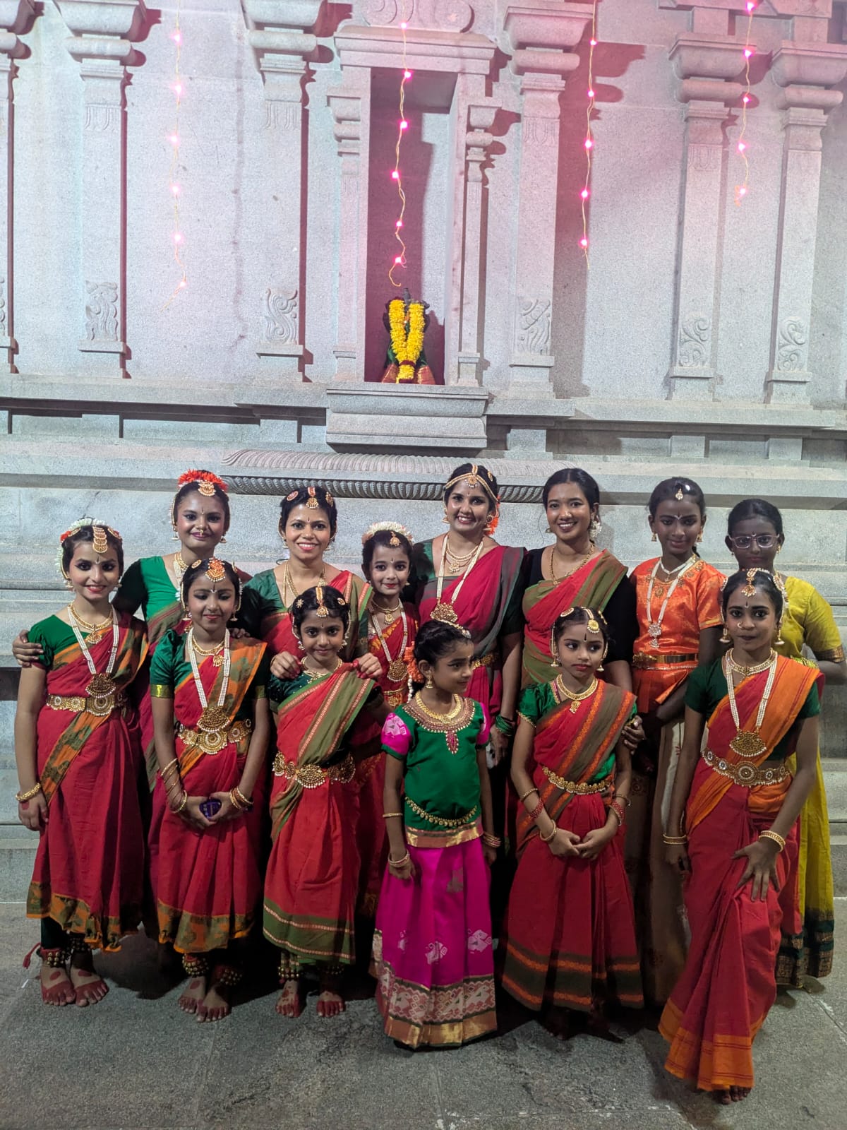 Dance students and teachers in traditional costume outside a temple